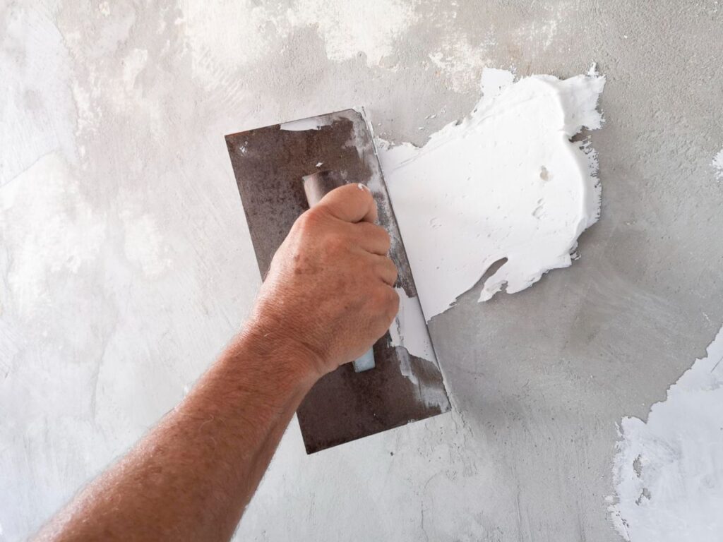 builder using plastering tool finishing old wall