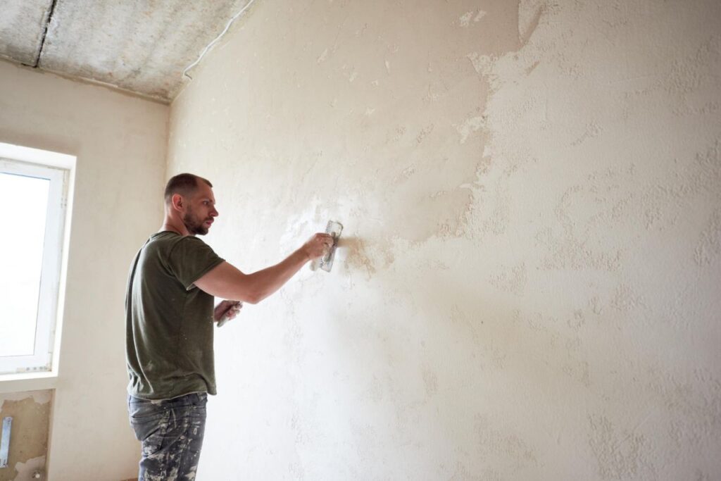 guy is making repairing apartment by putting putty walls