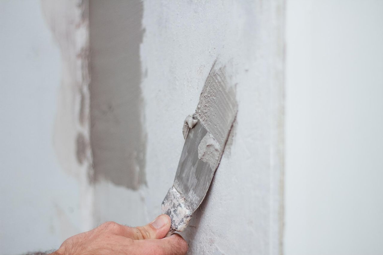 man hand with trowel plastering wall skim coating plaster walls